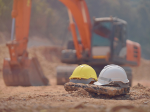 Excavation truck and construction safety helmets on the ground at a construction site, representing San Diego construction firm safety practices.